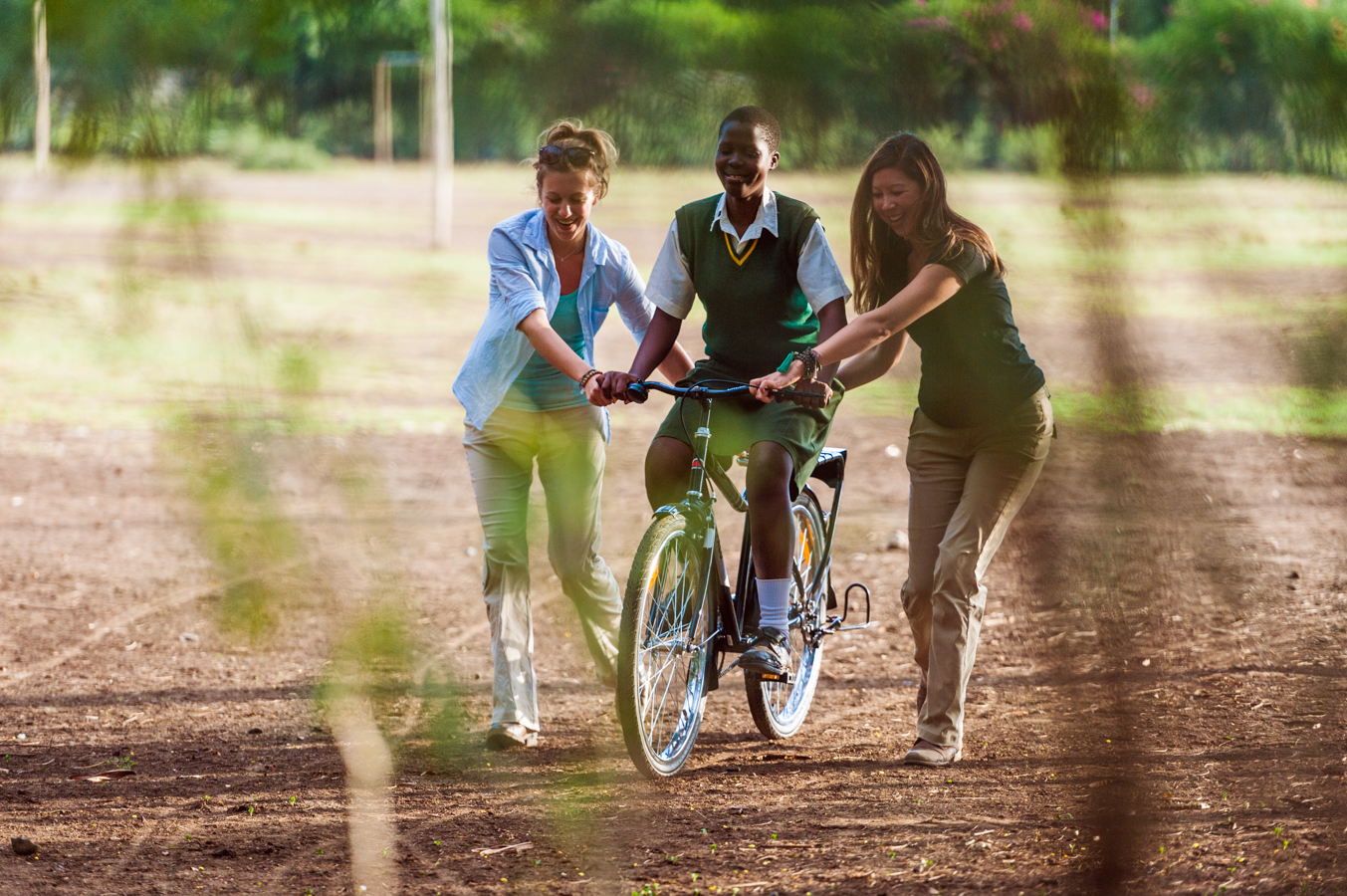Katie and Dana helping a schoolgirl in Kenya learn to ride a bike